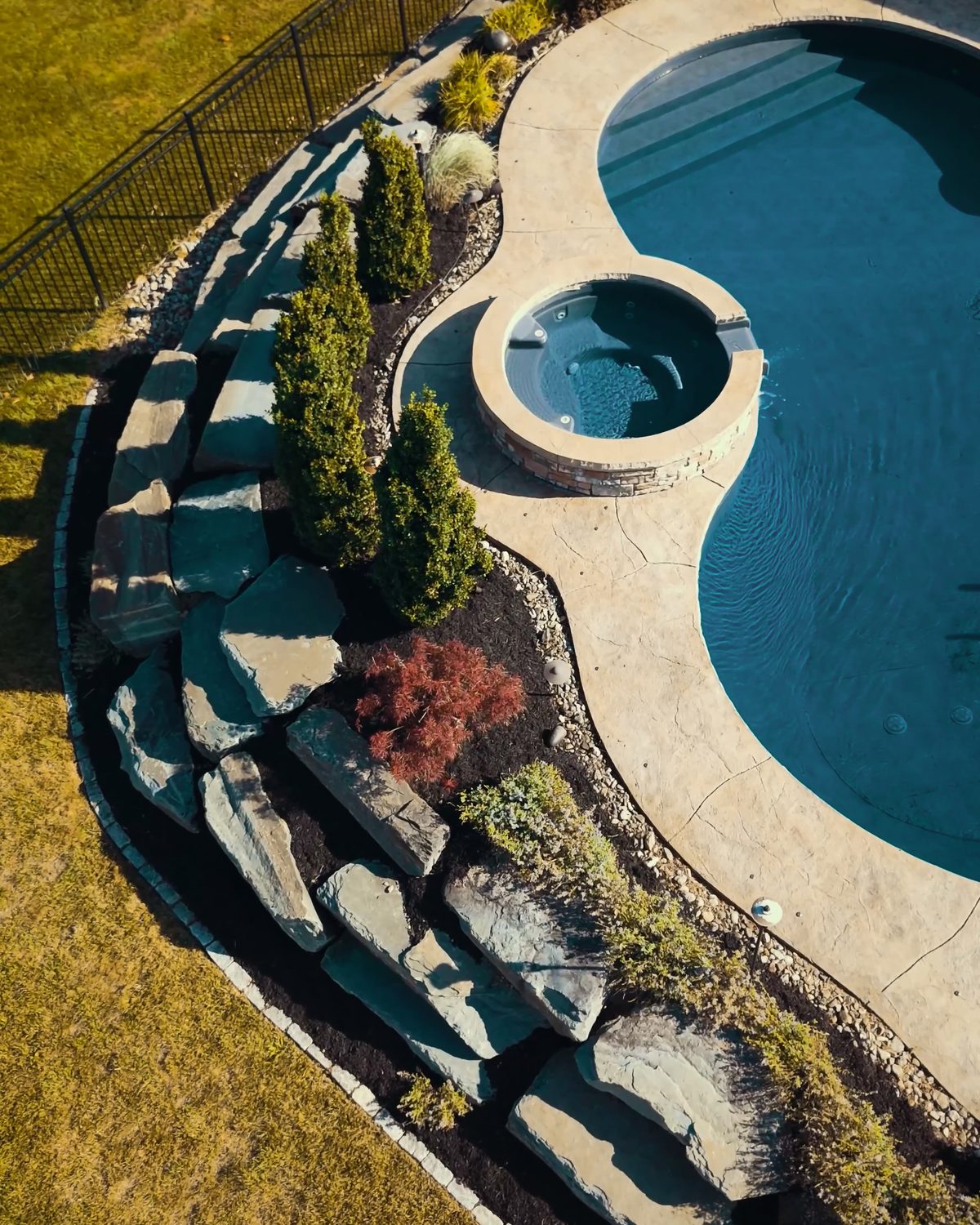 Aerial view of a pool surrounded by fresh landscaping and mulch beds