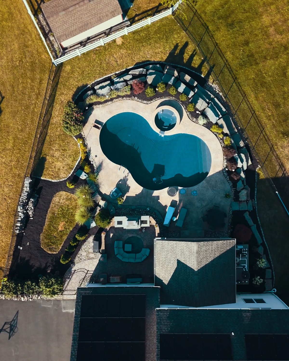 Aerial view of a pool and hot tub with mulch beds
